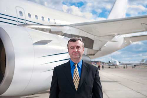 Man in suit stands by a commercial airplane.