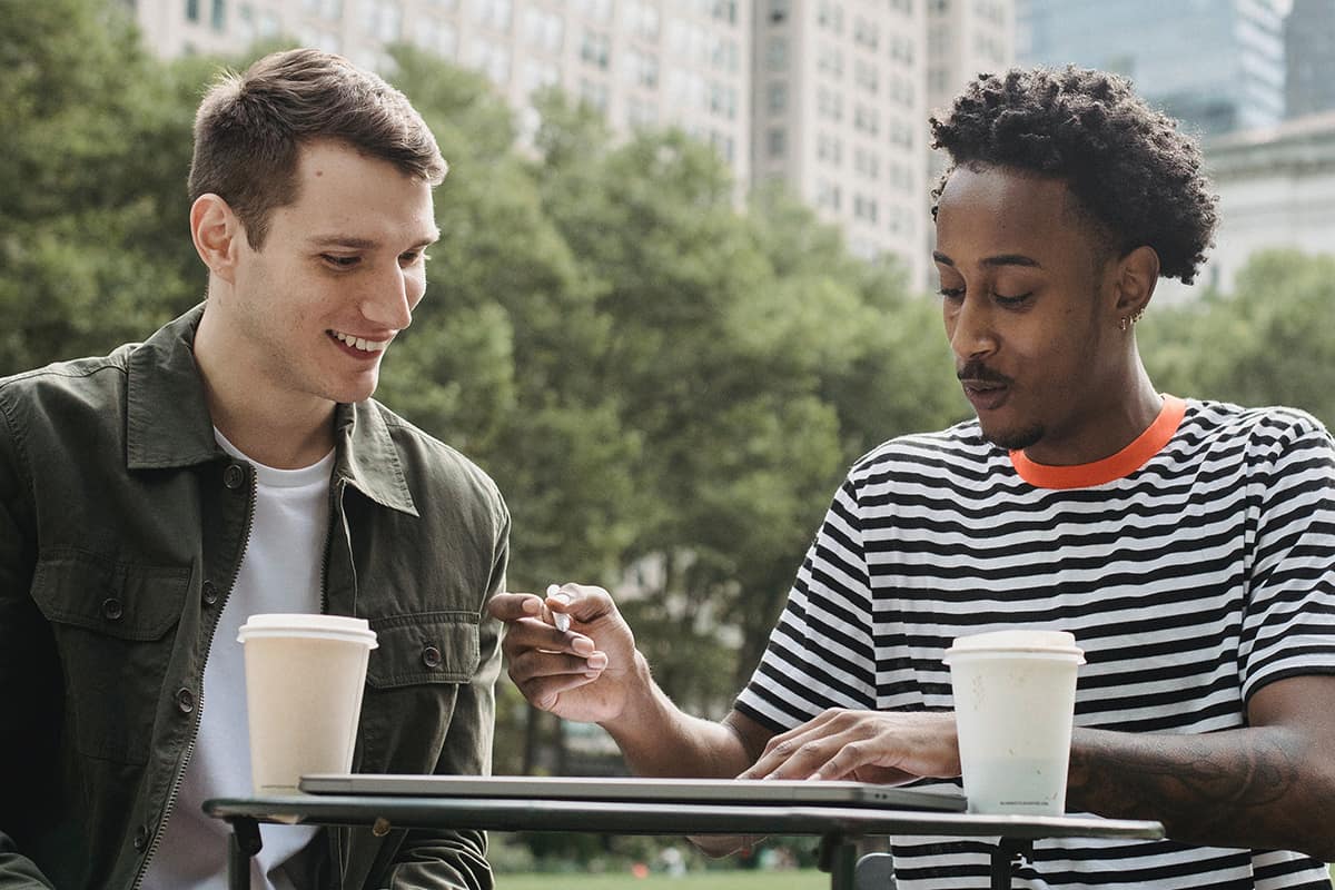 two men sit at a table with coffees