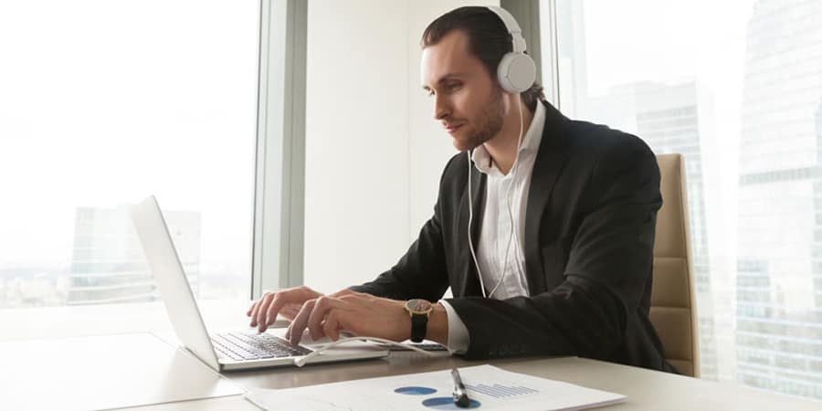 Man works on his computer while wearing headphones.