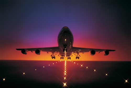 Commercial planes takes off in front of sunset.