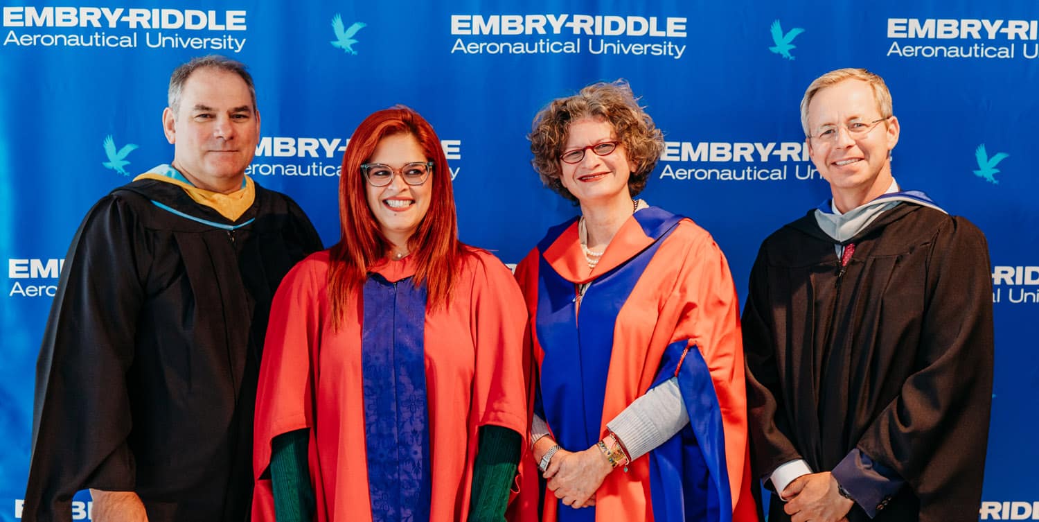 Four people wearing graduation regalia.