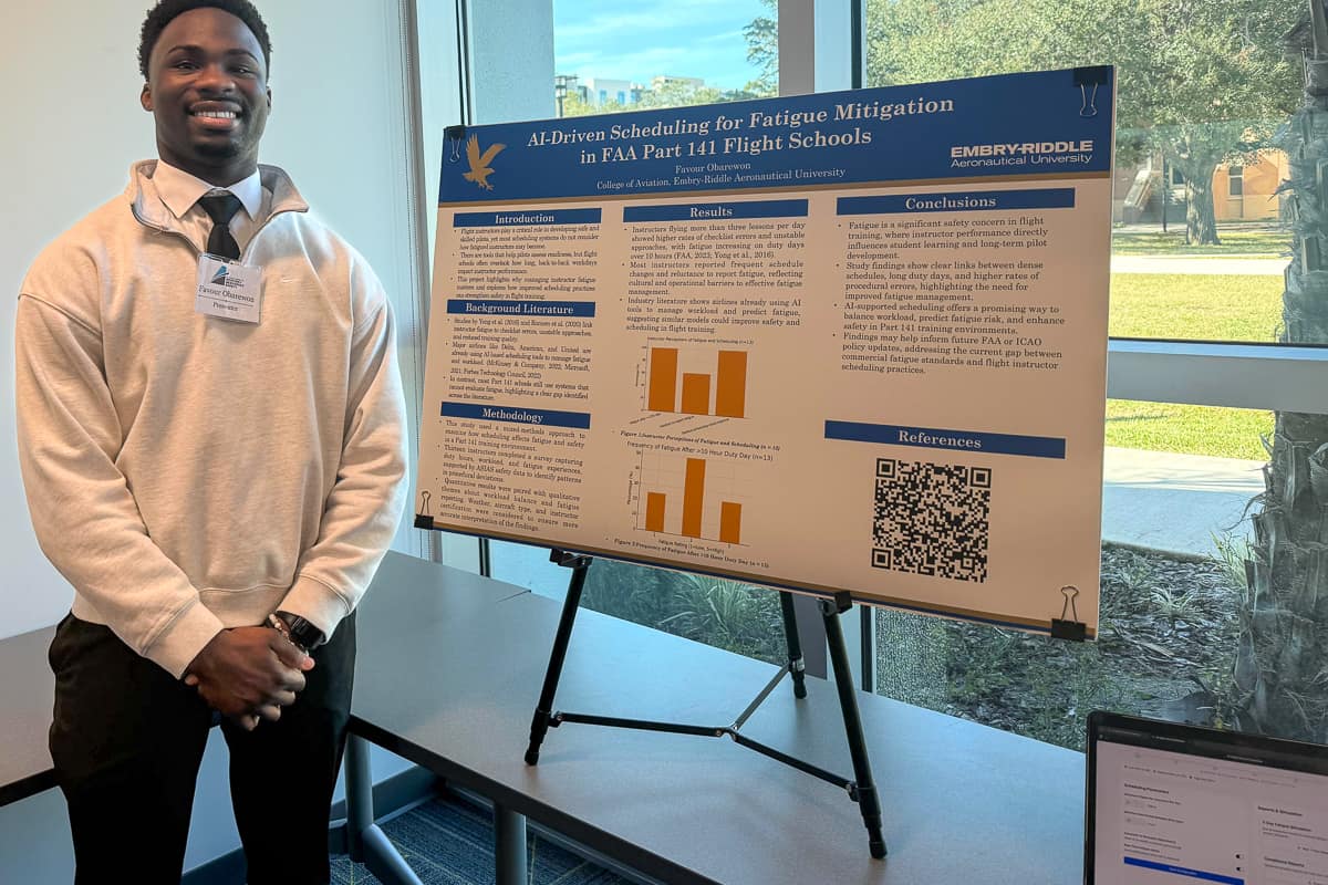 Man next to research poster and laptop