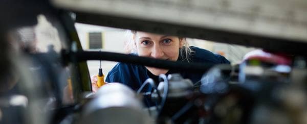a female engineer looks over a plane engine